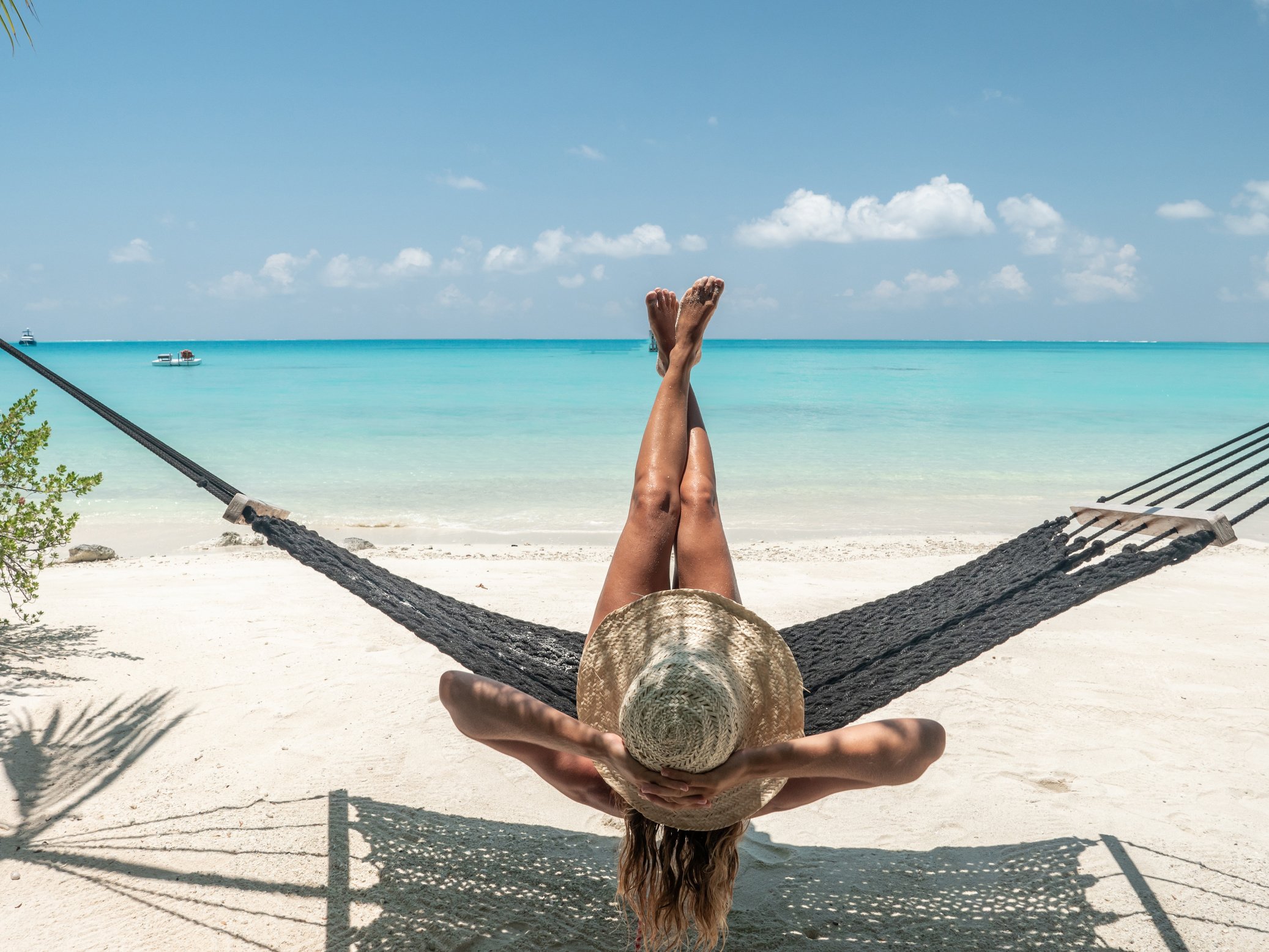 Young woman sunbathing on tropical beach, feet up